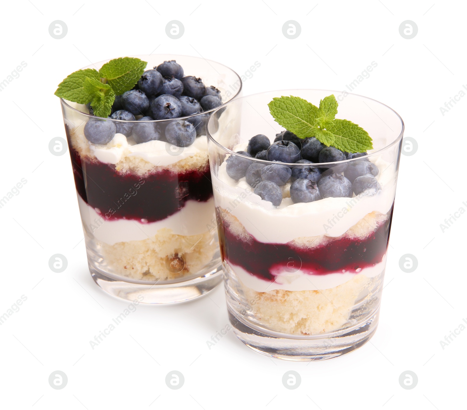 Photo of Tasty trifle dessert. Sponge cake, blueberries, jam and whipped cream in glasses isolated on white