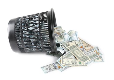 Photo of Many dollar banknotes and overturned trash bin isolated on white