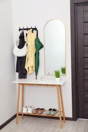 Mirror, rack with clothes and shoe storage bench in hallway. Interior design