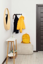 Photo of Mirror, rack with clothes and shoe storage bench in hallway. Interior design