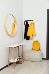 Photo of Mirror, rack with clothes and shoe storage bench in hallway. Interior design