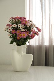 Stylish vase with beautiful flowers on white wooden table at home