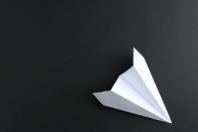 Photo of One handmade paper plane on black background, top view. Space for text