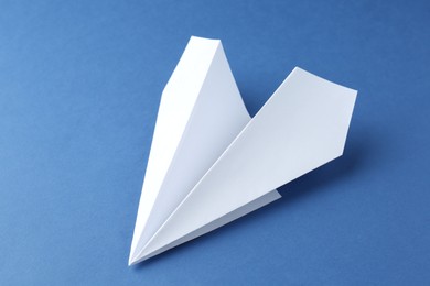 Photo of One handmade paper plane on blue background, closeup