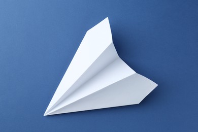 Photo of One handmade paper plane on blue background, top view