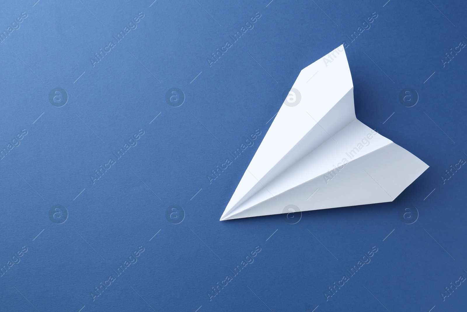 Photo of One handmade paper plane on blue background, top view. Space for text