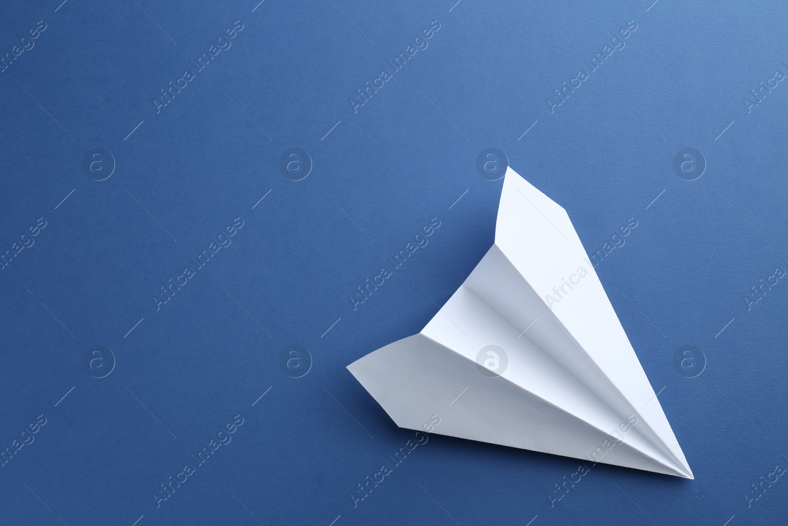 Photo of One handmade paper plane on blue background, top view. Space for text