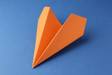 Photo of One handmade orange paper plane on blue background