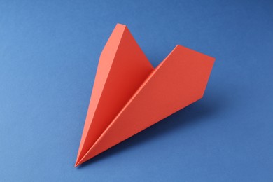 Photo of One handmade coral paper plane on blue background