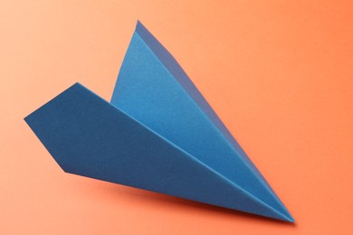 Photo of One handmade blue paper plane on orange background, closeup