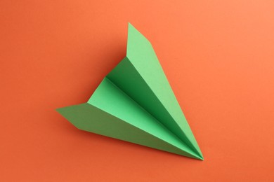 Photo of One handmade green paper plane on orange background, top view