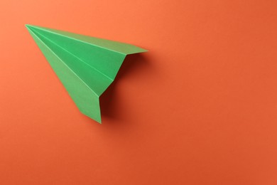 Photo of One handmade green paper plane on orange background, top view. Space for text