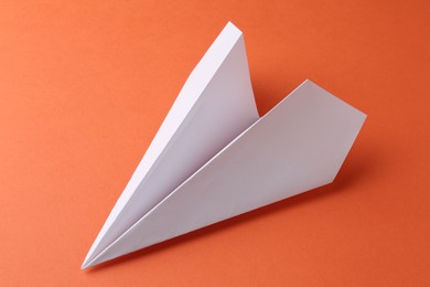 Photo of One handmade paper plane on orange background