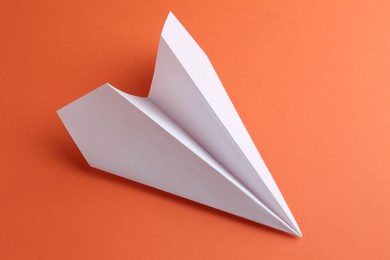 Photo of One handmade paper plane on orange background