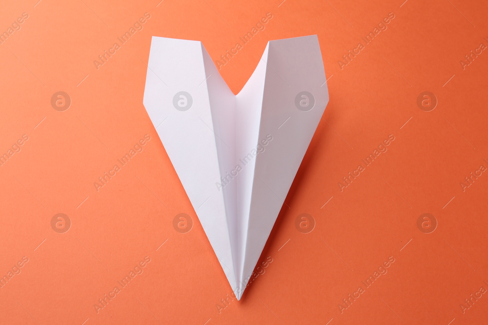 Photo of One handmade paper plane on orange background, above view