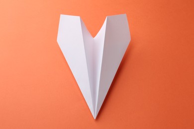 Photo of One handmade paper plane on orange background, above view