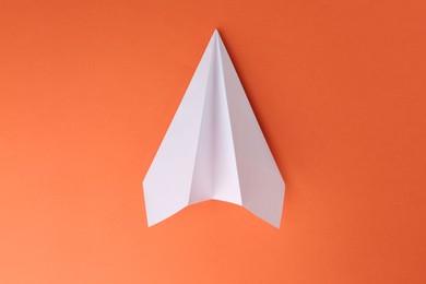 Photo of One handmade paper plane on orange background, top view