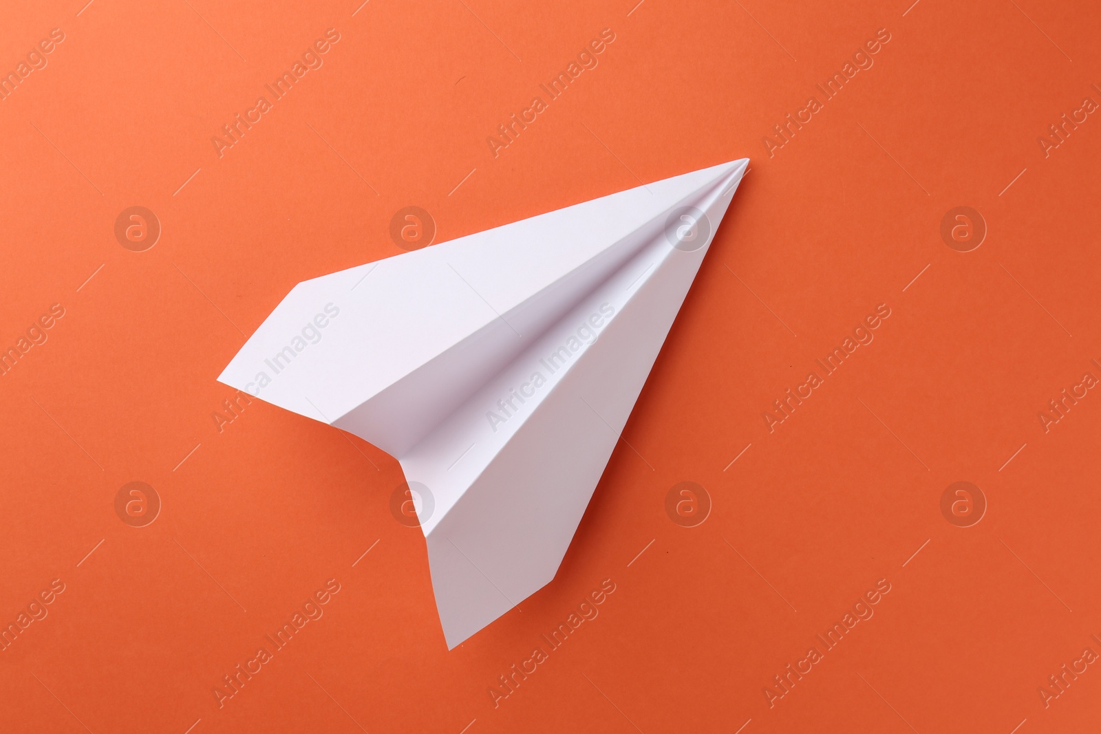 Photo of One handmade paper plane on orange background, top view