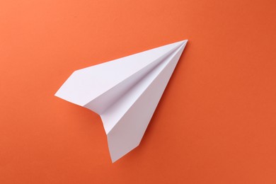 Photo of One handmade paper plane on orange background, top view