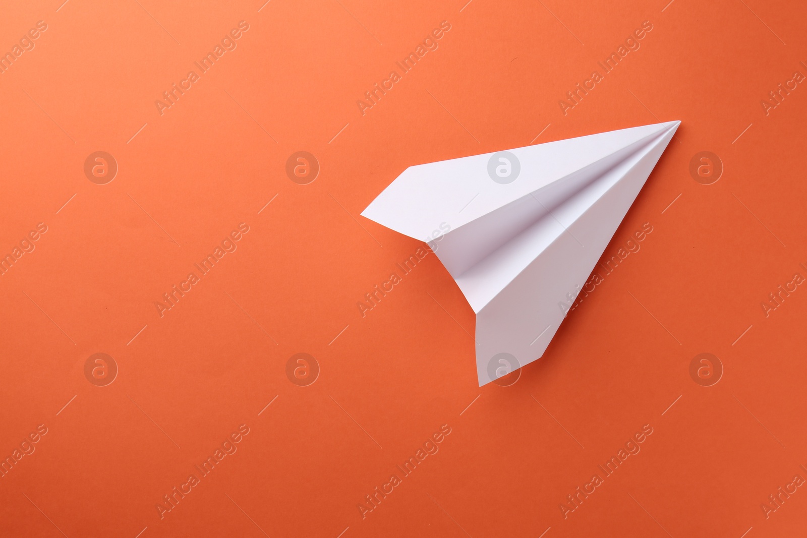 Photo of One handmade paper plane on orange background, top view. Space for text