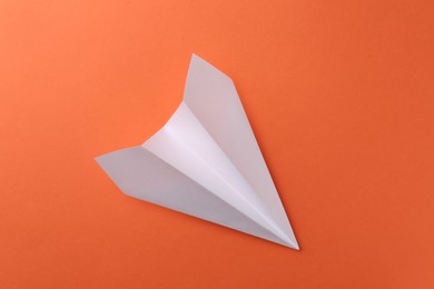 Photo of One handmade paper plane on orange background, top view