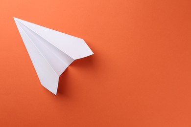 Photo of One handmade paper plane on orange background, top view. Space for text