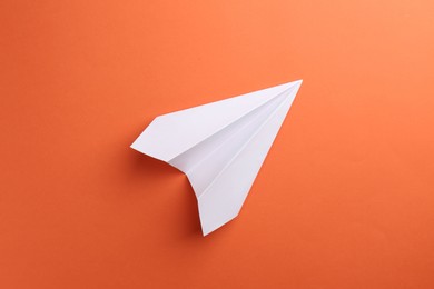 Photo of One handmade paper plane on orange background, top view