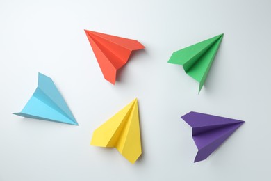 Photo of Handmade color paper planes on white background, flat lay