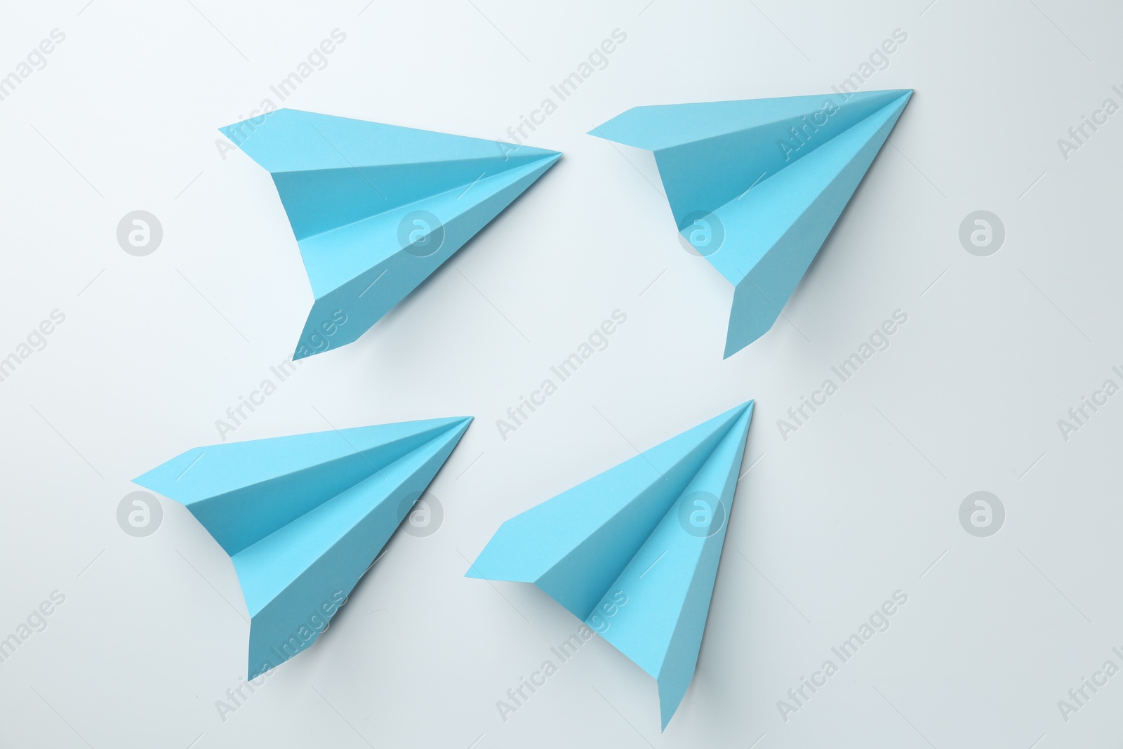 Photo of Handmade light blue paper planes on white background, top view