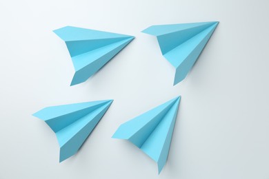 Photo of Handmade light blue paper planes on white background, top view