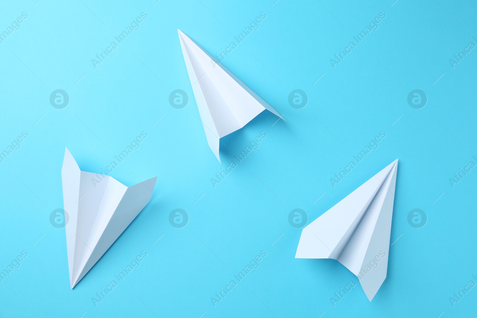 Photo of Handmade paper planes on light blue background, top view