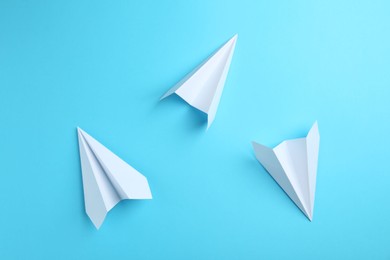 Photo of Handmade paper planes on light blue background, top view