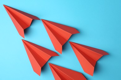 Photo of Handmade red paper planes on light blue background, top view