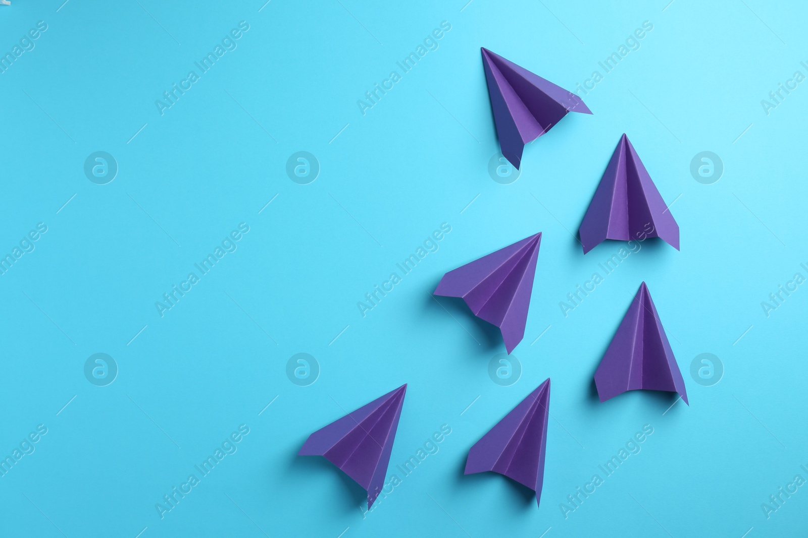 Photo of Handmade purple paper planes on light blue background, top view. Space for text