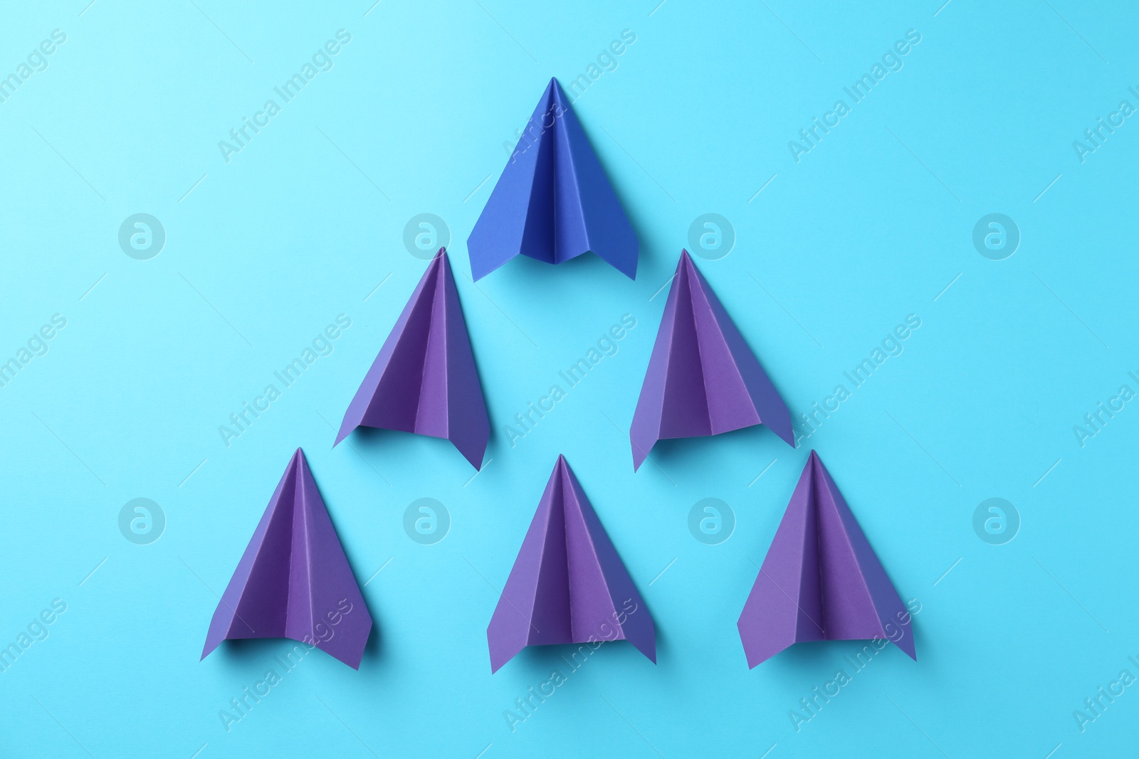 Photo of Handmade color paper planes on light blue background, flat lay