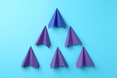 Photo of Handmade color paper planes on light blue background, flat lay