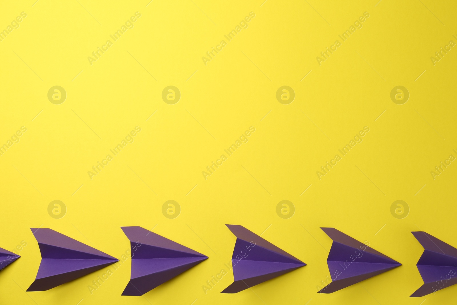 Photo of Handmade purple paper planes on yellow background, top view. Space for text