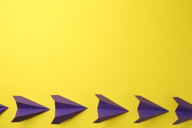 Photo of Handmade purple paper planes on yellow background, top view. Space for text