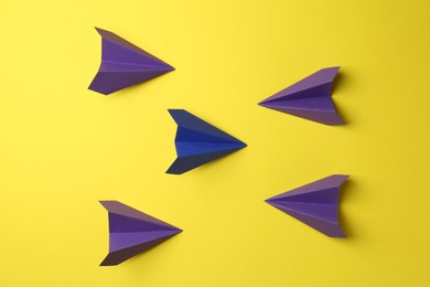 Photo of Handmade color paper planes on yellow background, top view