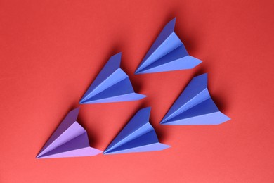 Photo of Colorful paper planes on red background, top view