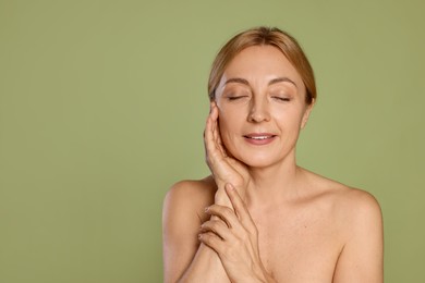 Portrait of smiling woman with healthy skin on green background