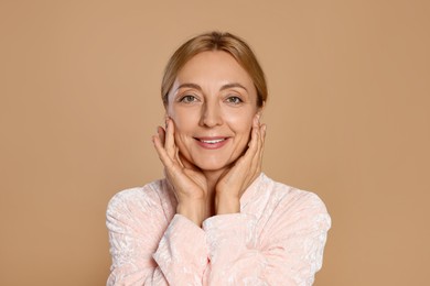 Portrait of smiling woman with healthy skin on beige background