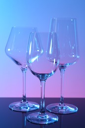 Photo of Empty glasses on table against color background