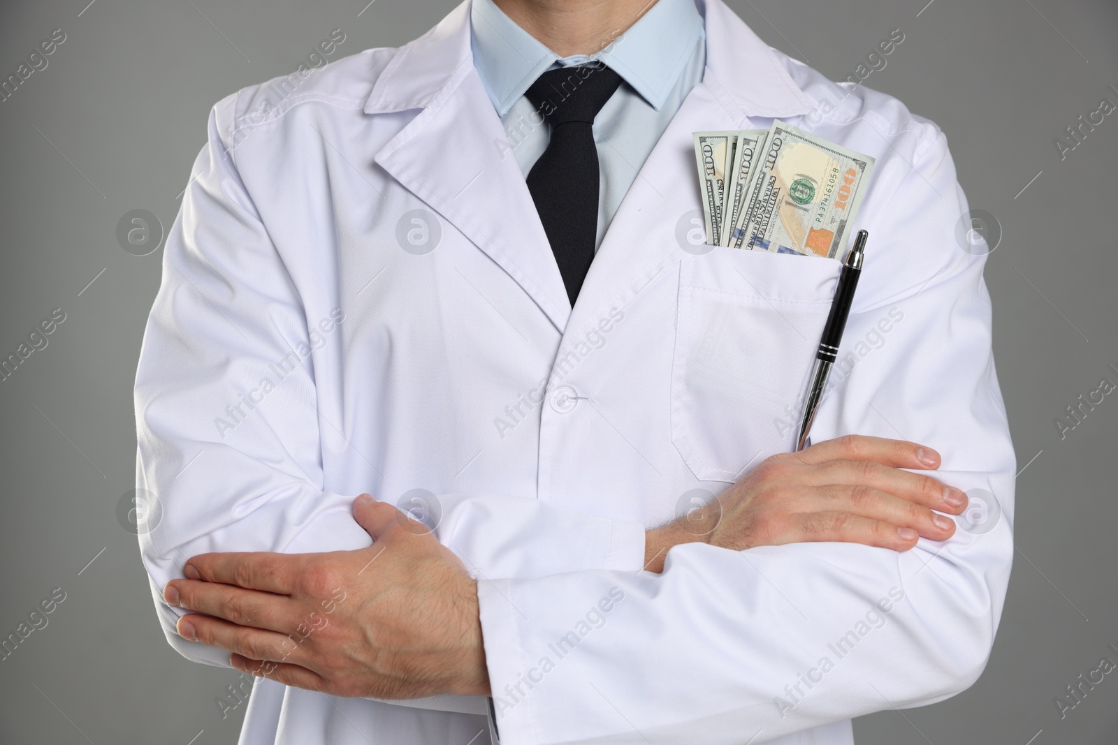 Photo of Corruption concept. Doctor with dollar banknotes on grey background, closeup