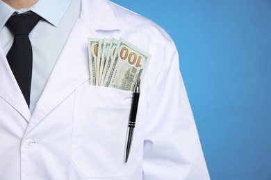 Corruption concept. Doctor with dollar banknotes on blue background, closeup