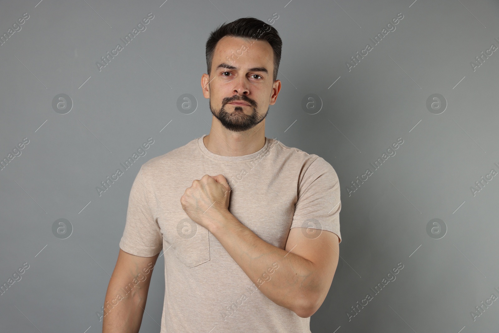 Photo of Man making promise on grey background. Oath gesture