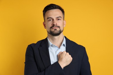 Man making promise on orange background. Oath gesture