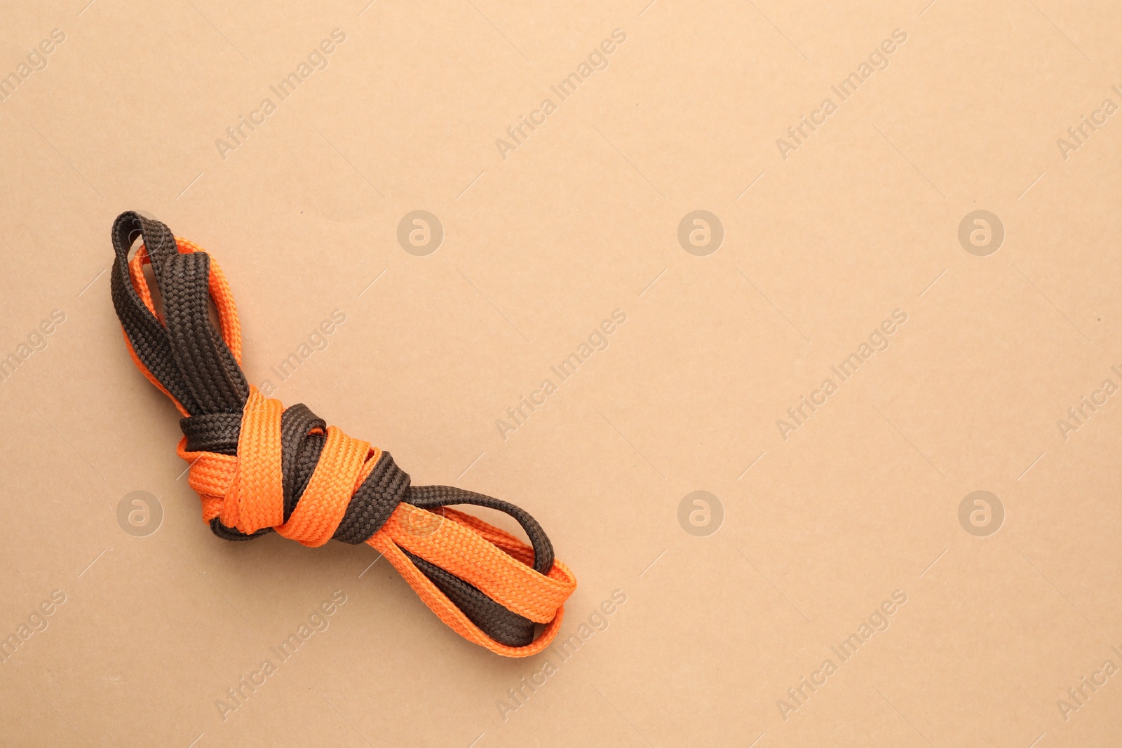 Photo of Shoelaces tied in knot on beige background, top view with space for text. Unity concept