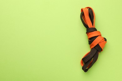 Photo of Shoelaces tied in knot on light green background, top view with space for text. Unity concept