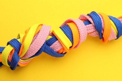 Photo of Colorful shoelaces tied in knots on yellow background, closeup. Unity concept